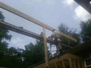 Carpenter setting a ridge beam over a new addition frame — Ice Dam Removal by Roofing Brothers in Minetto