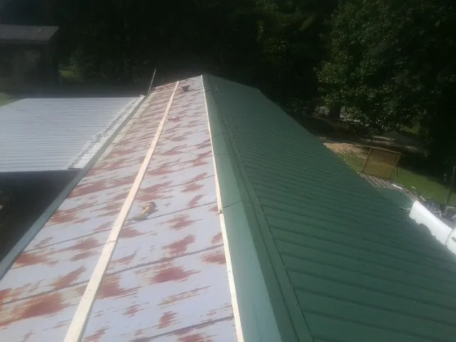 Old rusted panels beside newly installed green metal roofing — Wind Damage Roof Repair by Roofing Brothers in Minetto
