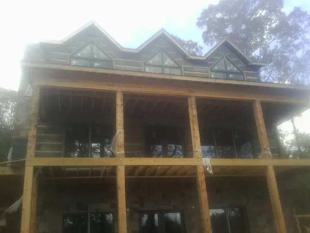 Dormers and porch framing on a large log home under construction — Roof Coating work by our crew in Minetto