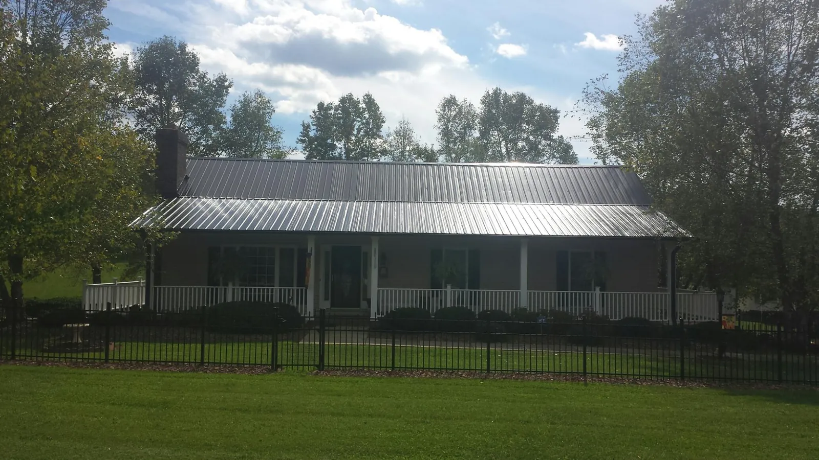 Gray metal roof on a brick ranch with a full width front porch — Gutter Guard Installation work by our crew in Minetto