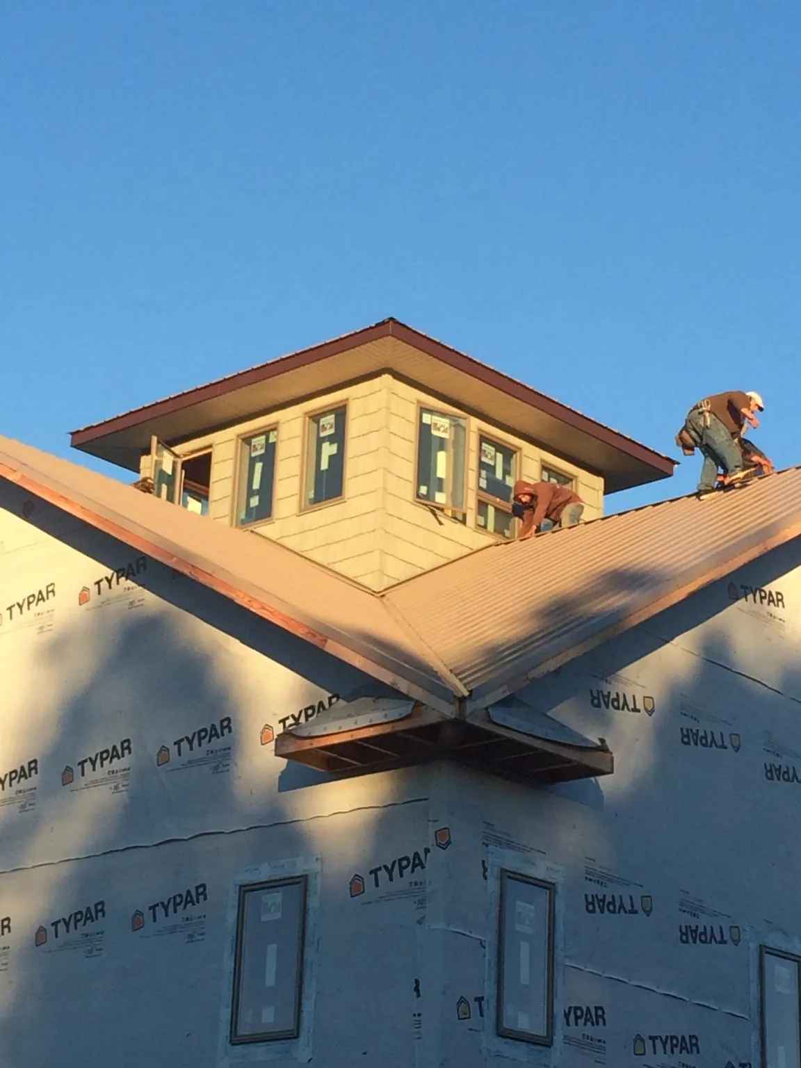 Roofers working around a rooftop cupola on a new metal roof at sunset — Roof Waterproofing in Minetto by Roofing Brothers